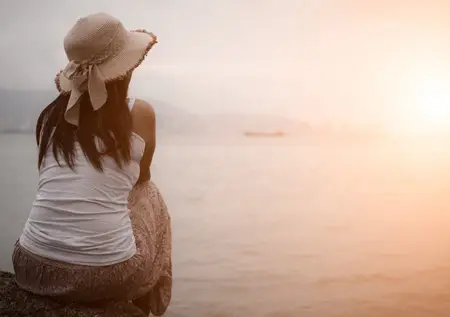 Lady sitting by the beach watching the sunset