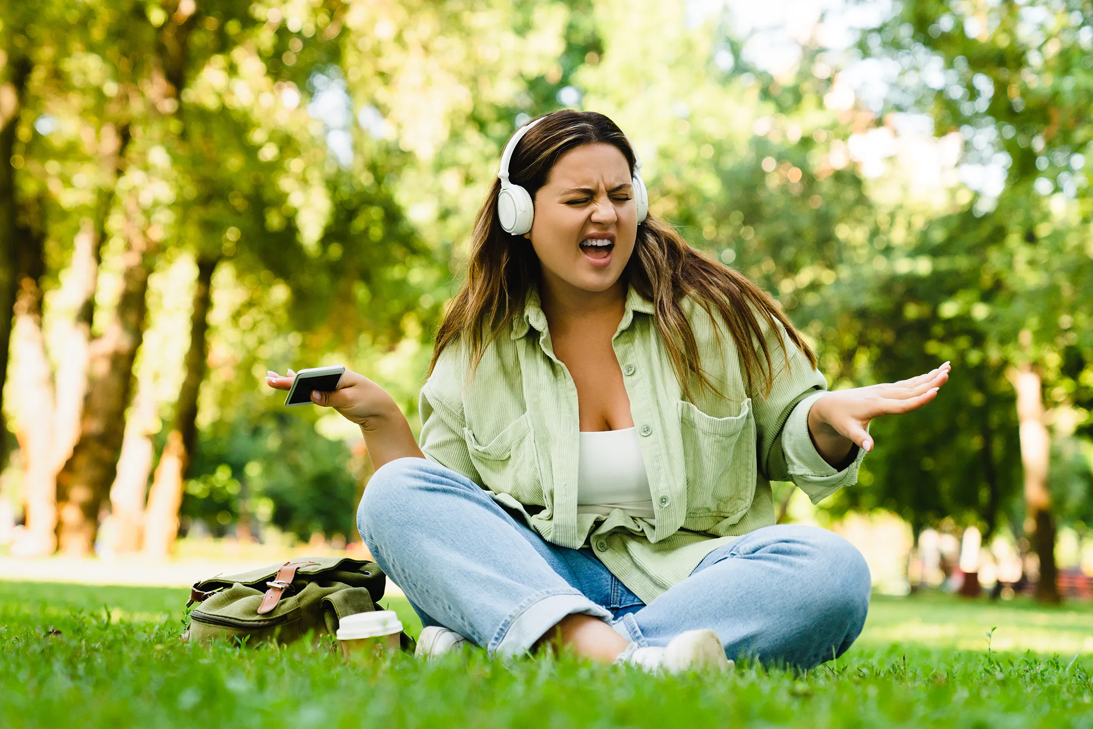 Dancing woman relaxing after college university listening to the music in headphones in campus park