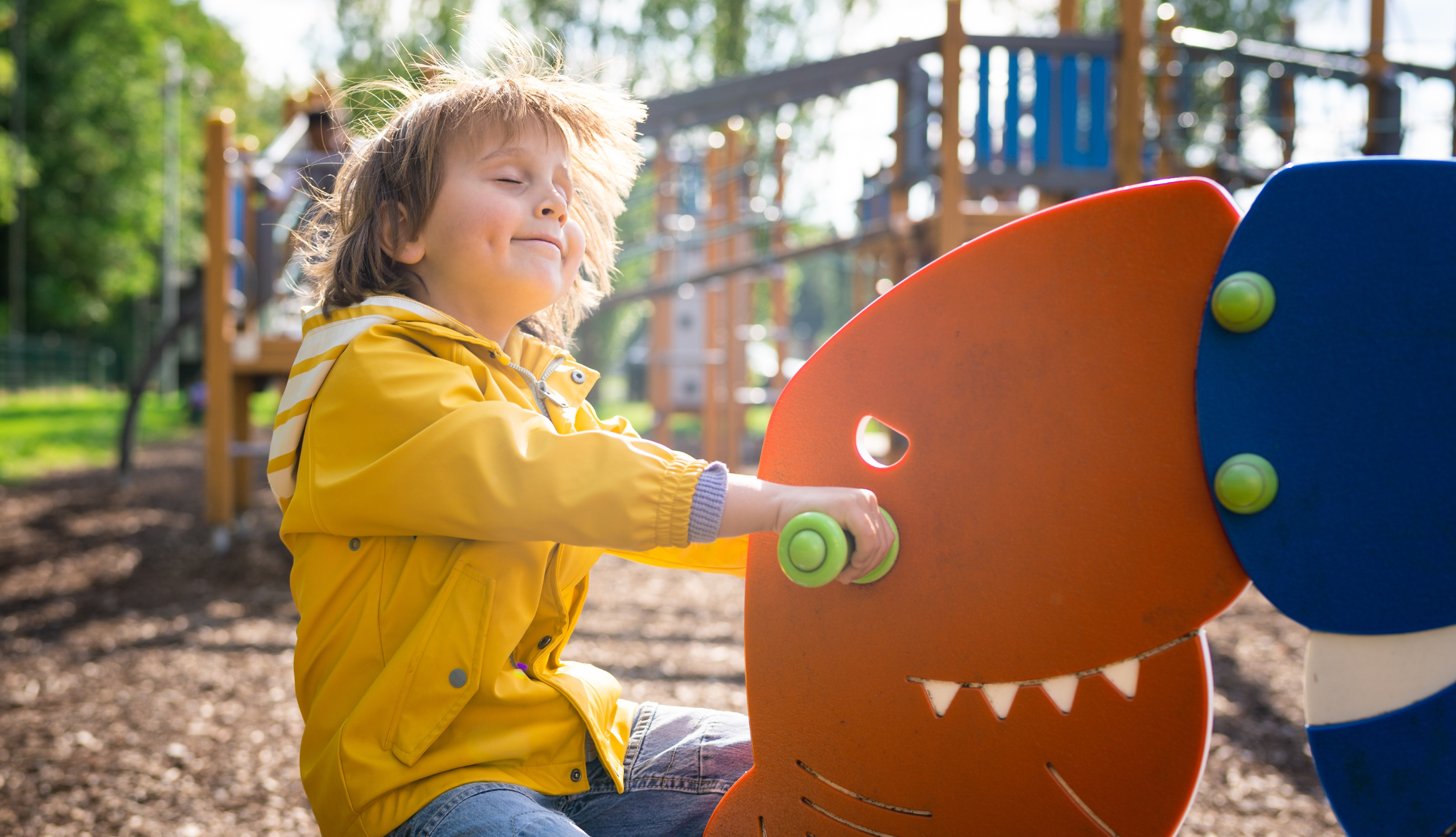 A young boy practicing ways to attain emotional intelligence by swinging on a playground dinosaur